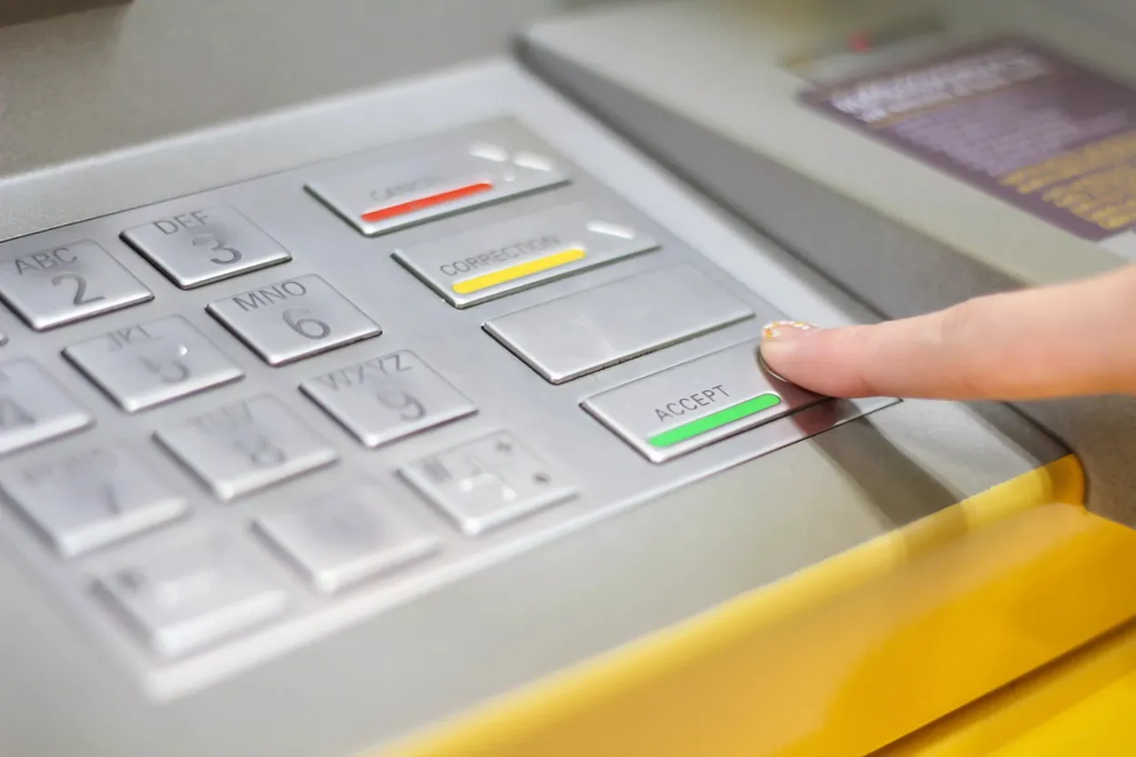 Une main appuie sur le bouton "ACCEPTER" d'un terminal argenté.